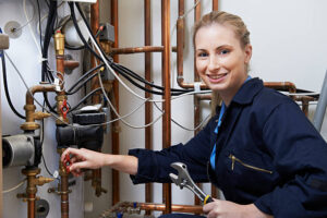 Female Plumber Working On Central Heating Boiler