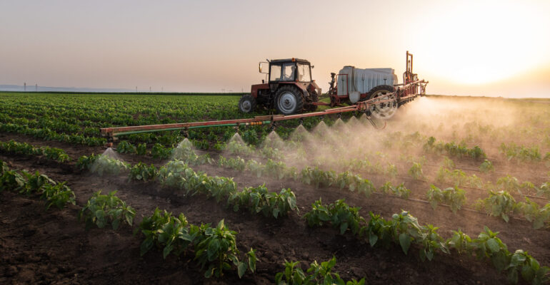 Tractor spraying pesticides on vegetable field with sprayer at spring Tractor spraying pesticides on vegetable field with sprayer at spring